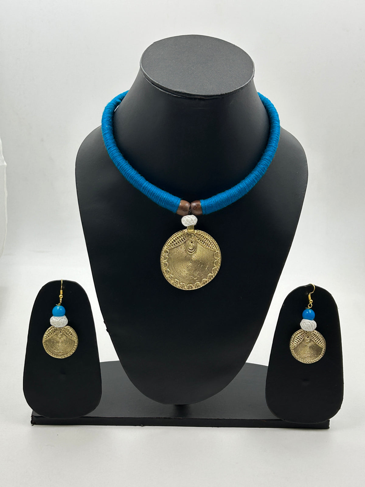Arohi Blue Dokra handmade necklace set displayed on mannequin with brass round dokra pendant, blue thread necklace, and matching dokra earrings