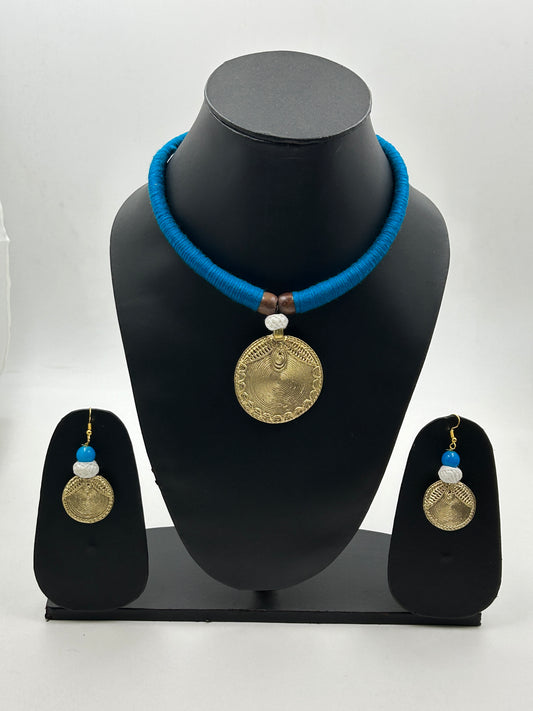 Arohi Blue Dokra handmade necklace set displayed on mannequin with brass round dokra pendant, blue thread necklace, and matching dokra earrings
