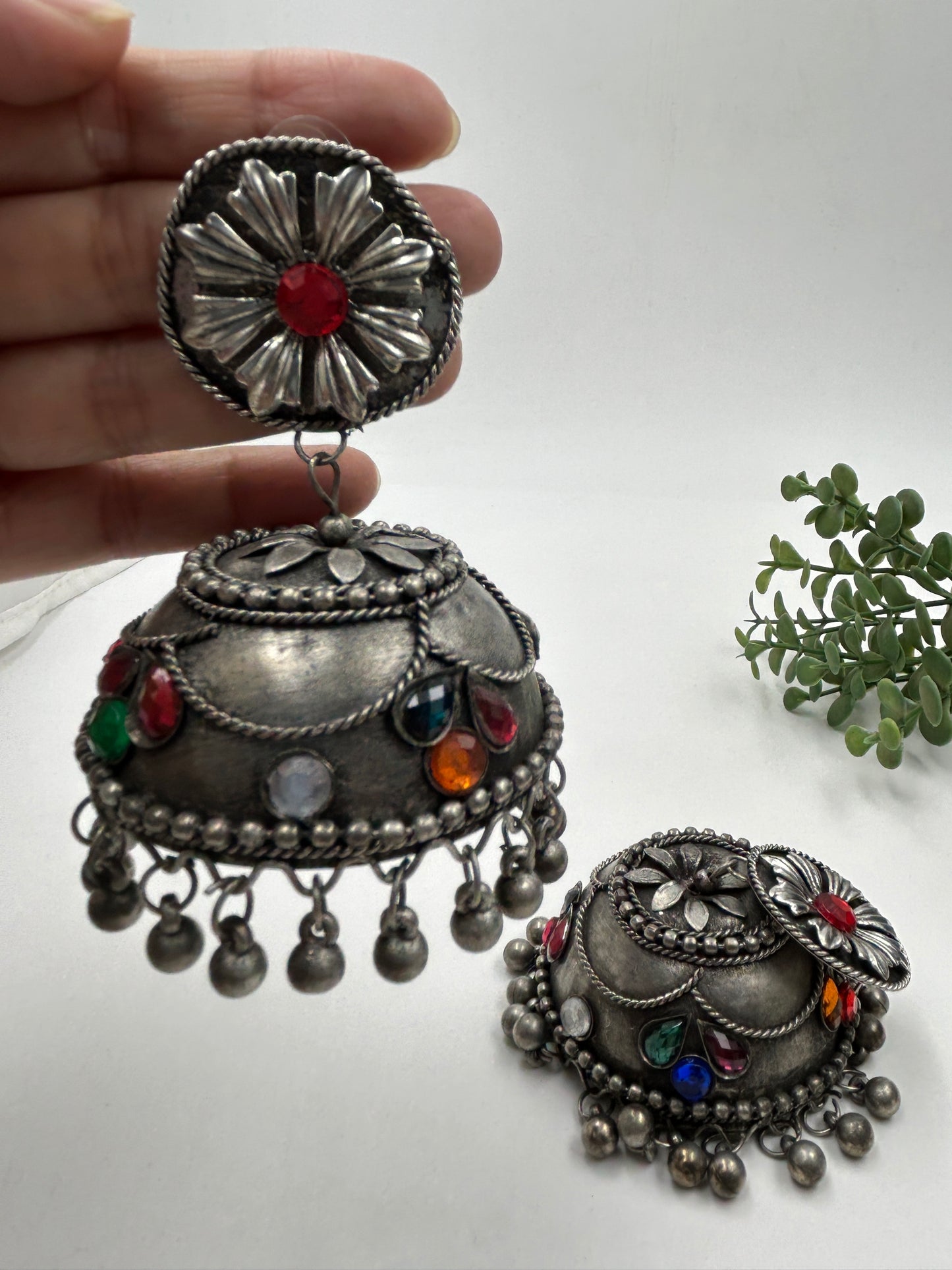 Banhi black polished jhumka earrings displayed in hand and placed on flat surface, showing detailed design with no sound hanging beads, tribal inspired statement earrings