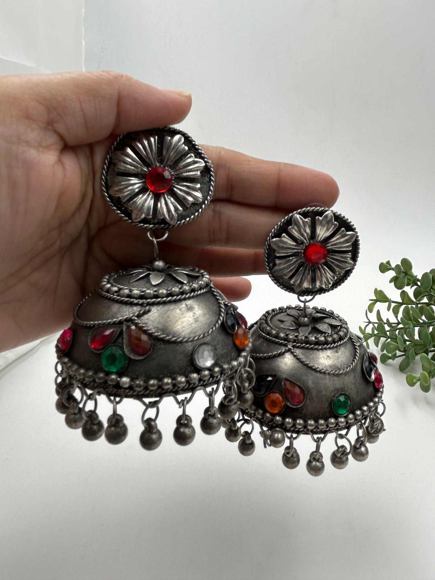 Banhi black polished jhumka earrings shown in hand as a pair for size reference, with intricate detailing and silent hanging beads, bold ethnic jewelry