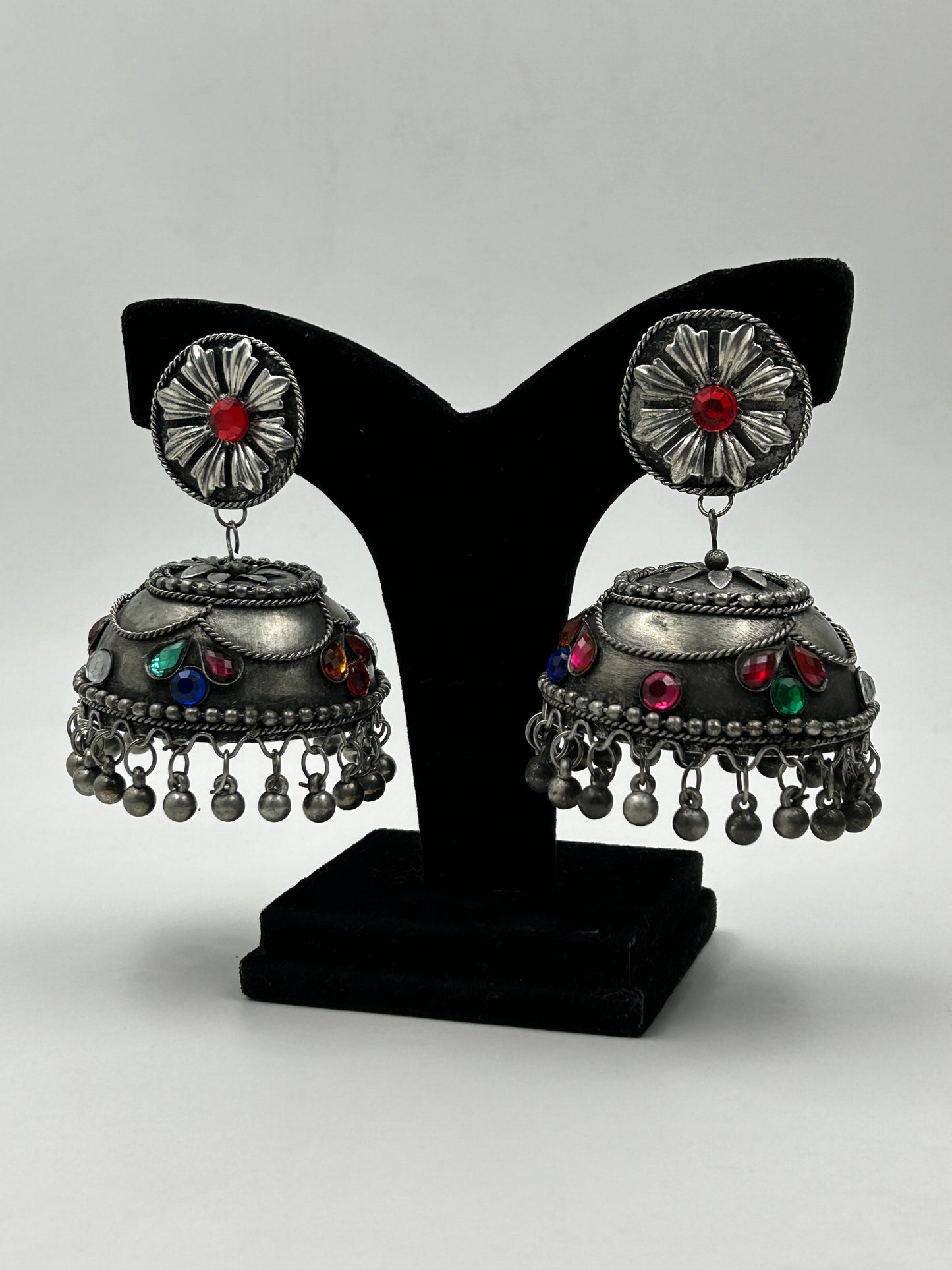 Banhi black polished jhumka earrings displayed on stand with detailed design and multicolor accents, featuring no sound hanging beads, bold ethnic statement earrings