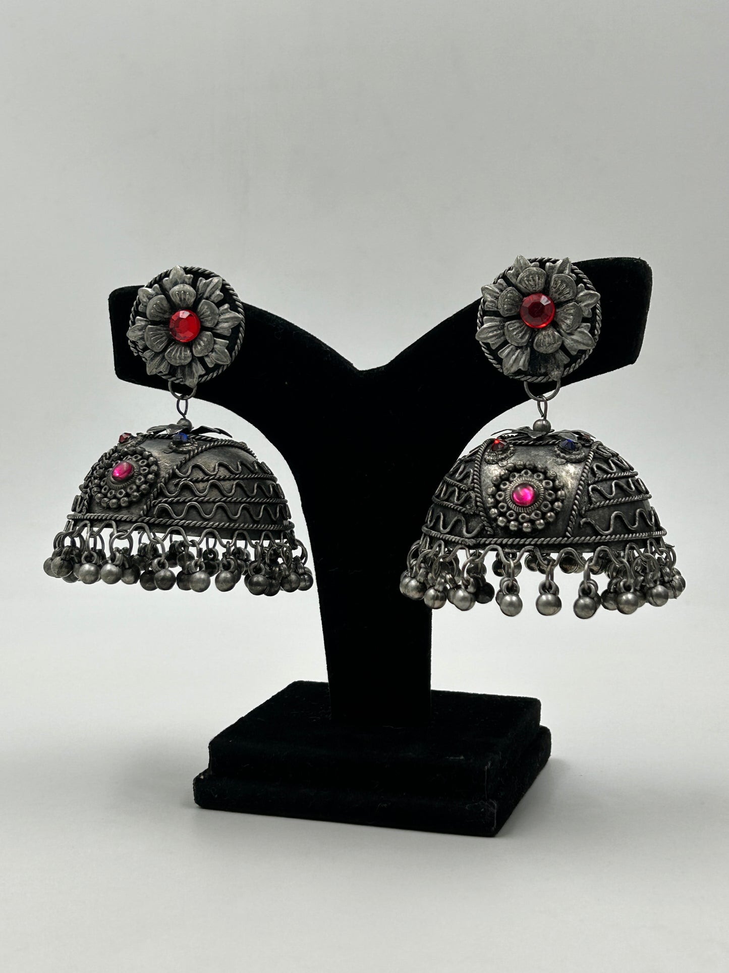 Bhavi black polished jhumka earrings displayed on stand with intricate detailing and silent ghungroo hangings, bold tribal inspired statement earrings for ethnic wear