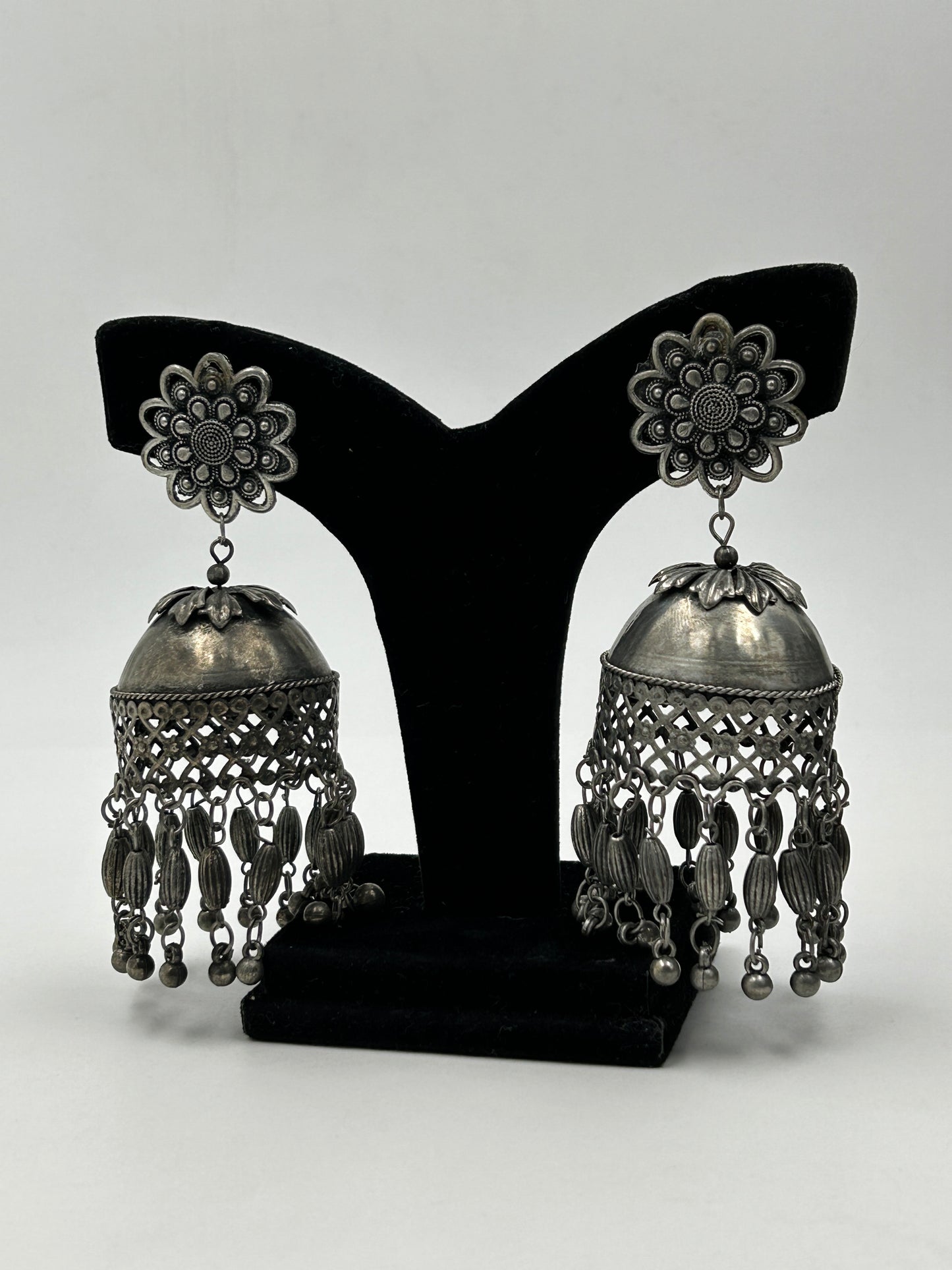 Darsha black polished jhumka earrings displayed on stand with floral stud and dome design, long tribal statement earrings for ethnic wear