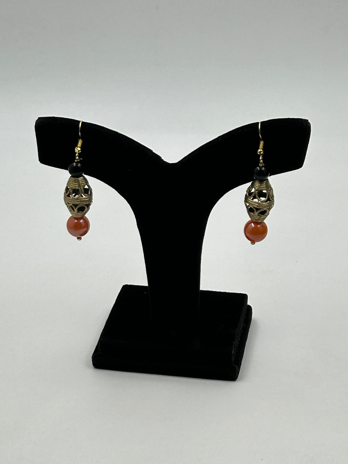 Elara Handmade Dholak Dokra Earrings with Orange Beads on Earring Display Stand
